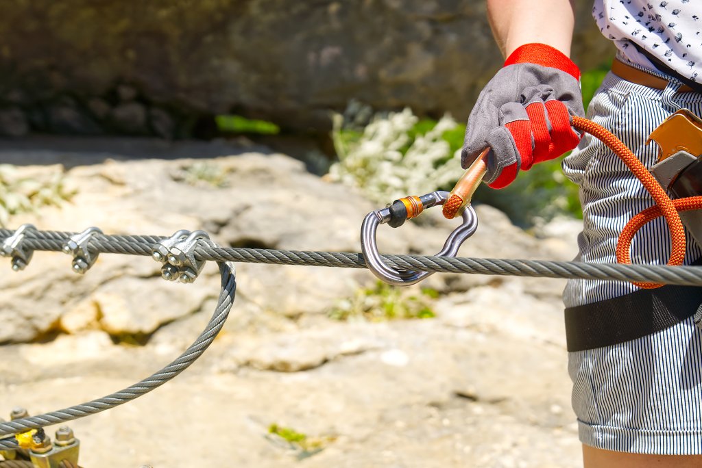 Drahtseilklemmen und Karabiner als Verbindungselemente bei der Sicherung an einem Drahtseil auf einer Bergwanderung.